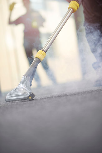a male cleaning contractor steam cleans an office carpet in a empty office