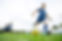 Young boy in a blue football kit running forward to kick a yellow and blue football on a green grass pitch