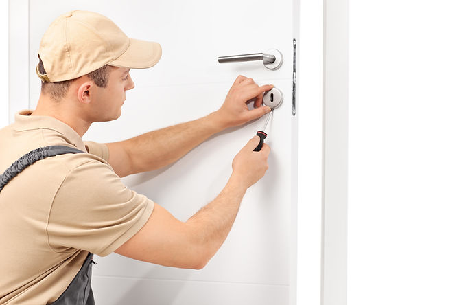 A locksmith installing a lock on a white door with a screwdriver