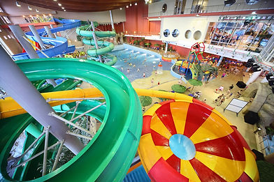 Large indoor waterpark facility with multiple slides, wave attractions, and guest activity areas