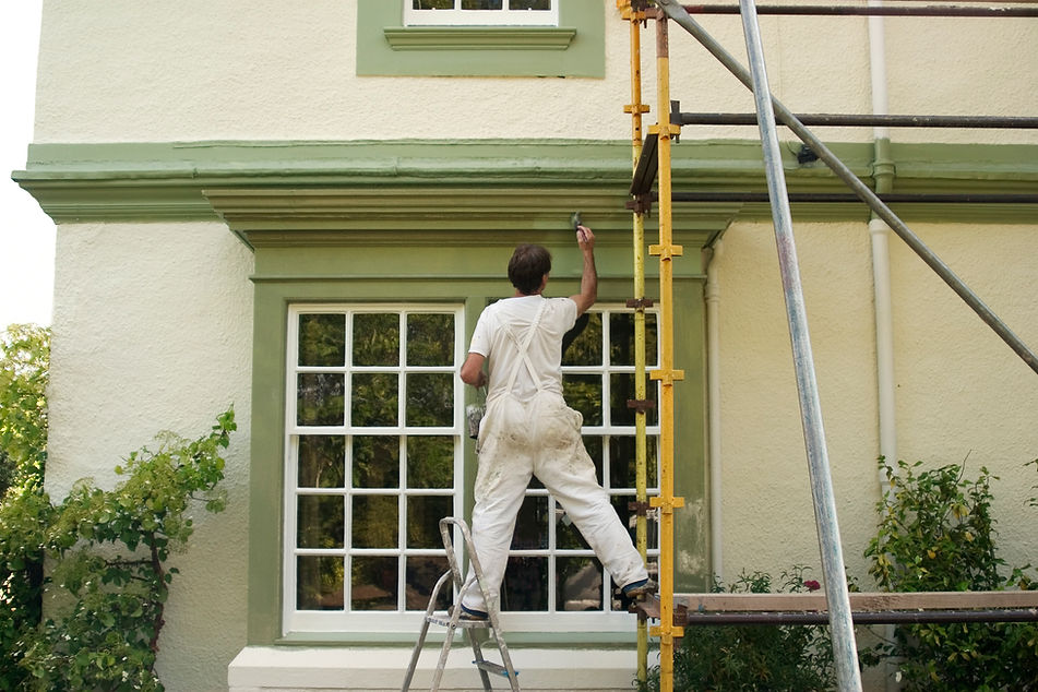 Painter and decorator painting an exterior section above a window green