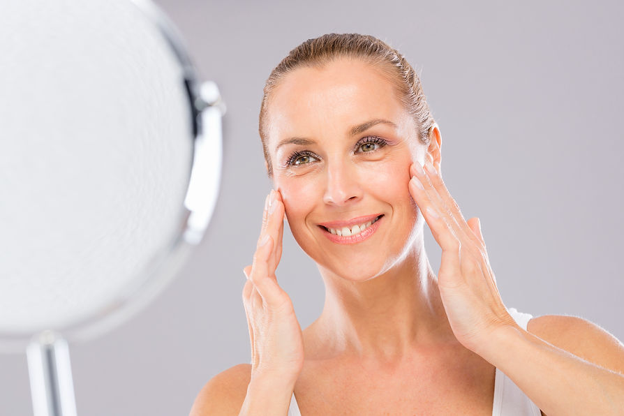 Middle aged woman with care and tenderness face skin looking to the mirror