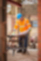 A man in an orange vest and safety glasses works on a construction site