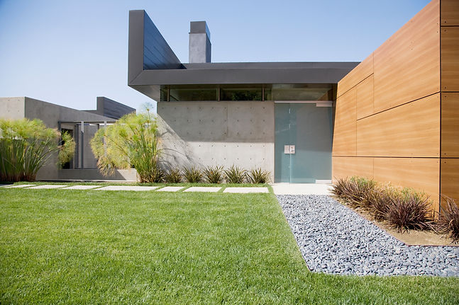 Neat vibrant green lawn bordered by a crisp modern pathway filled with dark decorative slate chippings