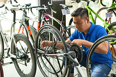 Asian man reattaching a bike chain in a bike shop