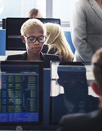 Eine Frau, die an ihrem Computer in einem Handelsraum sitzt
