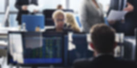 A woman sitting by her computer in a trading room