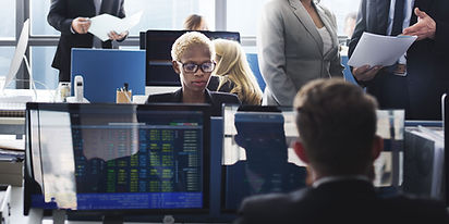 A woman sitting by her computer in a trading room