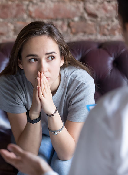 Menina sentada de frente ouvindo terapeuta durante sessão de psicoterapia.