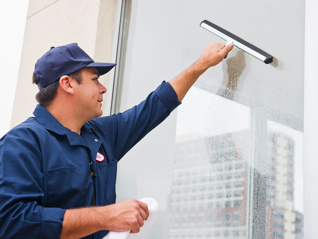 Close-up of a window cleaner using a squeegee on an internal glass partition