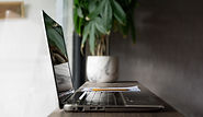 Image of a open laptop placed on a desk with a coffee mug remote workspace setting