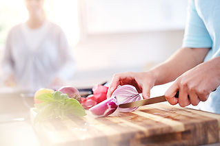 Woman slicing red onion on cutting board in kitchen