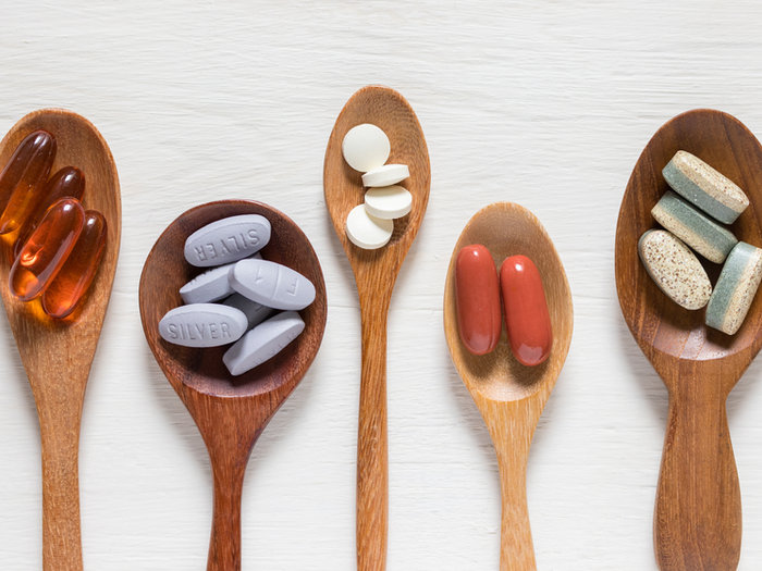Wooden spoons each holding different capsules and tablets