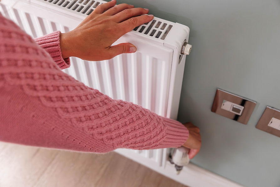 Close up of a person adjusting a white thermostatic radiator valve on a home radiator
