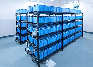 Rows of blue lithium-ion batteries are neatly arranged on industrial metal racks in a clean