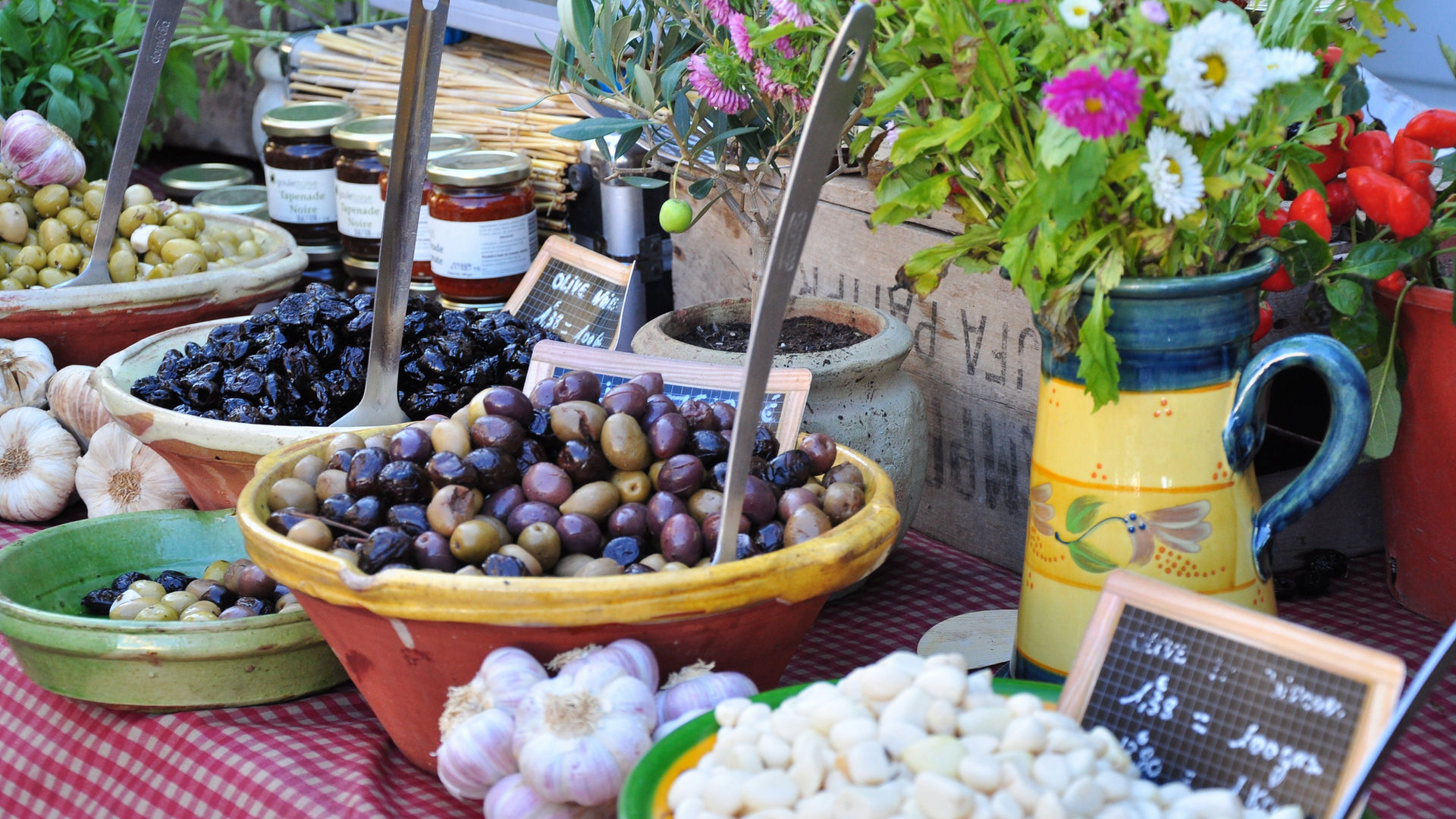 Étal de marché provençal : olives, tapenade et ail dans des plats en terre cuite