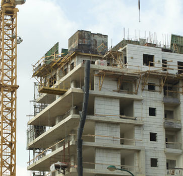 Ein hoher Kran neben einem unfertigen Hochhaus mit Gerüst