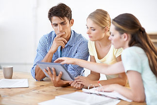 Three young entrepreneurs collaborating on a digital tablet in a bright modern office space