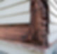 Damaged wooden siding with extensive rot and decay at the corner of a house