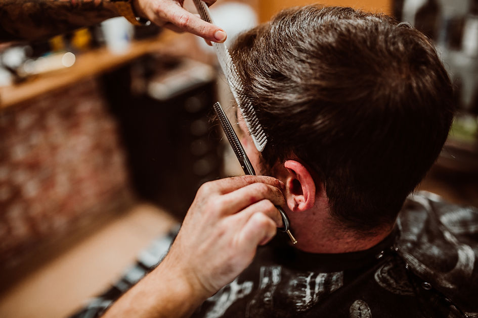 Image of a man in a barber shop with scissors and a comb
