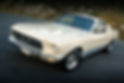Classic Ford Mustang in cream colour with chrome accents parked on a road