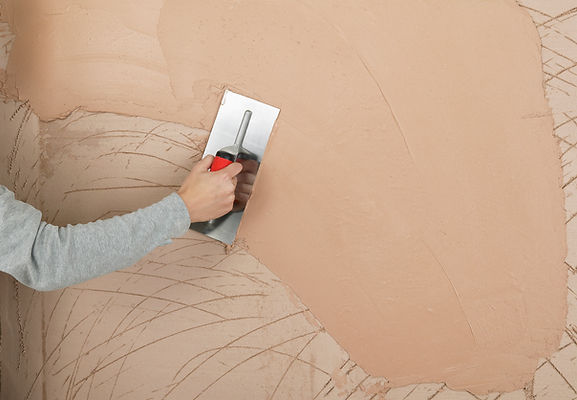 Professional plasterer smoothing wet plaster onto wall surface with a trowel