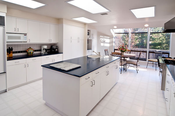 View of a contemporary kitchen and dining space with a dark worktop island
