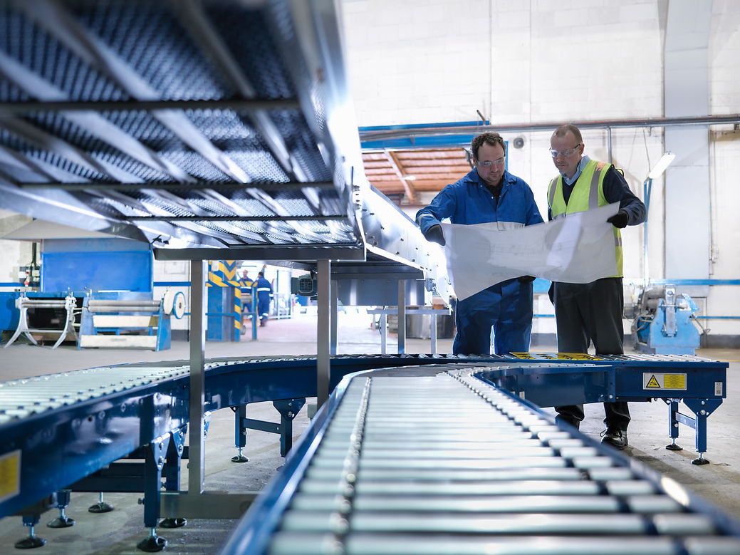 Engineers inspecting new conveyor in engineering factory
