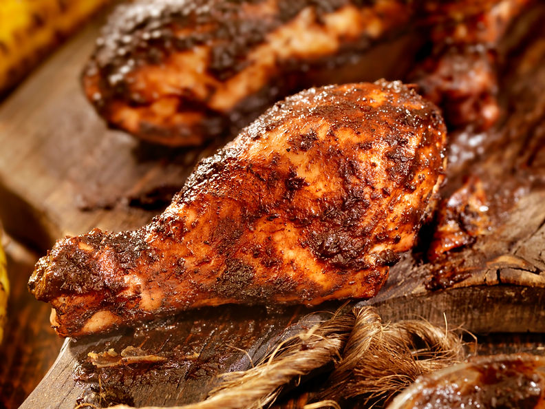 Close-up of a juicy, grilled chicken drumstick coated in a rich, dark seasoning