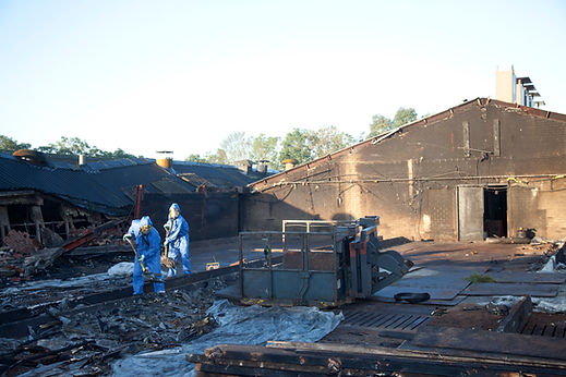Asbestos removal in progress at a demolition site with piles of construction rubble and debris