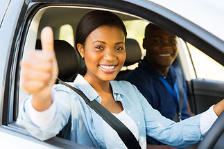 A happy young female driver gives a thumbs up while in a car