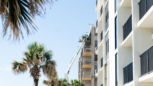 Multistory building under construction with balconies and nearby palm trees