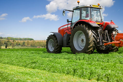 Red tractor parked in a green agricultural field under a blue sky