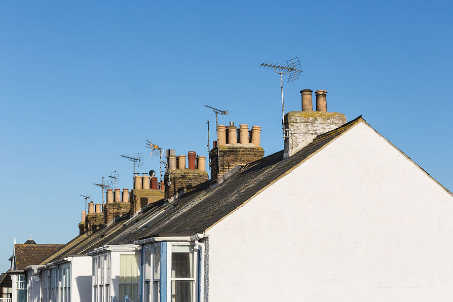 Roof tops with chimneys and TV aerials on terrace, row houses, homes. against a blue sky