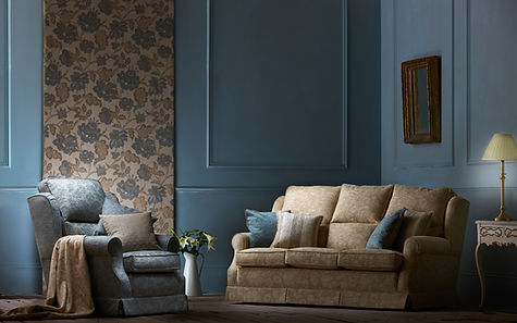 A cosy living room with a beige sofa and blue armchair, adorned with plush cushions