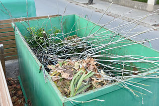Skip container filled with garden waste including soil and branches