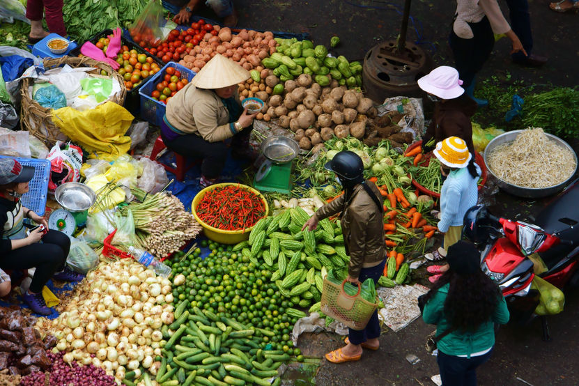 Mensen verkopen en kopen groenten op de openluchtmarkt in Vietnam