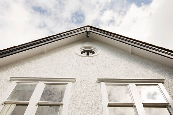 Close up architectural view of house roofline and white rendered wall