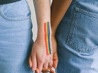 Picture of two people holding hands. One of them has a rainbow on their arm