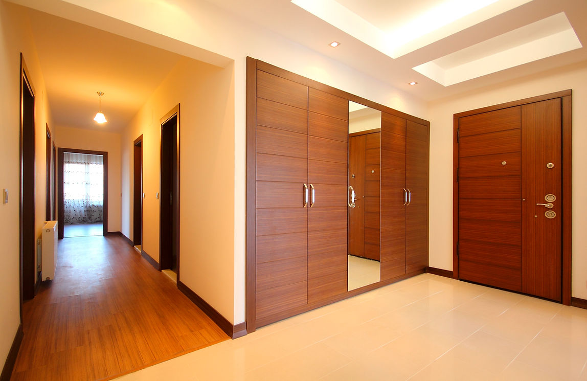 Modern hallway with wooden floors, a mirrored closet, and several wooden doors