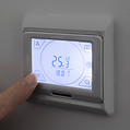 Person adjusting digital thermostat