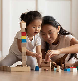 Asian mom helping her kid building blocks