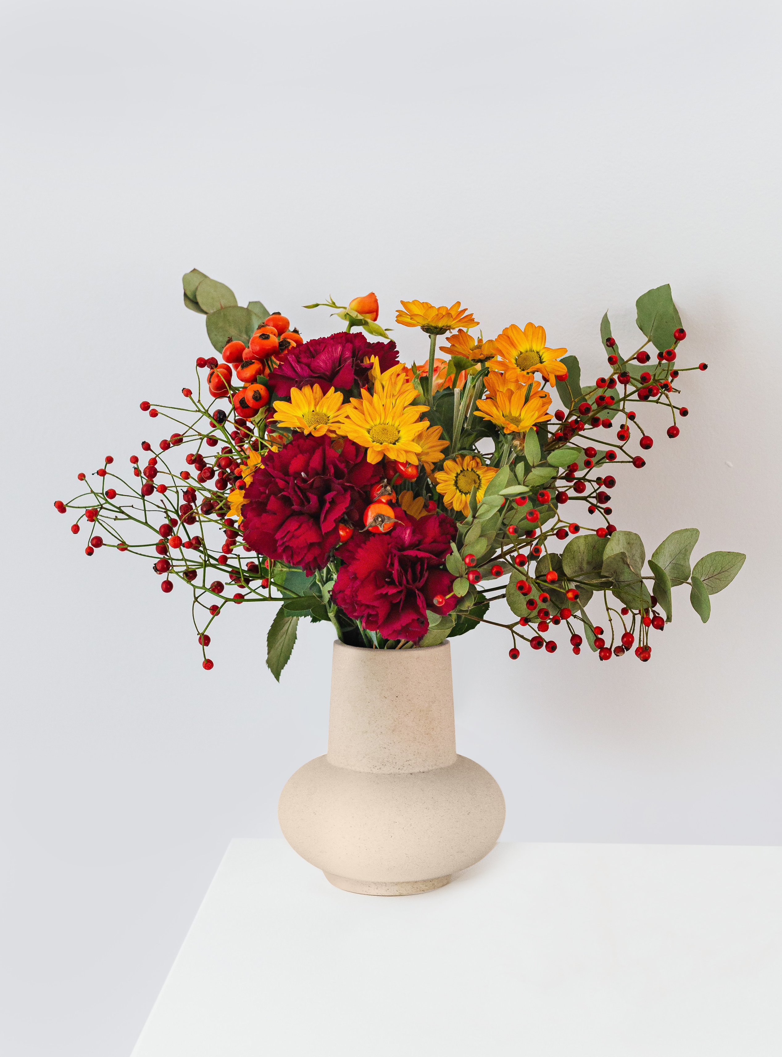 Blumiger Herbststrauß in beigefarbener Vase