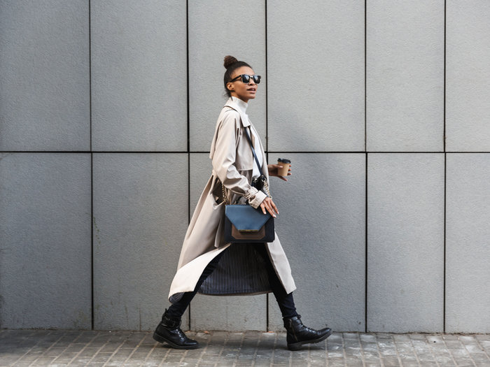 Woman in a coat walking past a concrete wall
