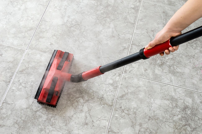 A steam mop cleaning a light grey tiled floor
