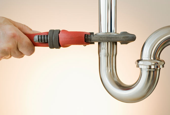 Hand tightening a white PVC plumbing P-trap pipe with a red and black wrench