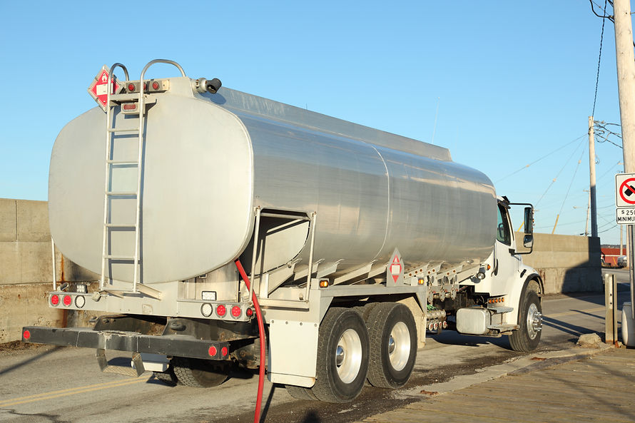 A large, silver tanker lorry parked on the side of a road