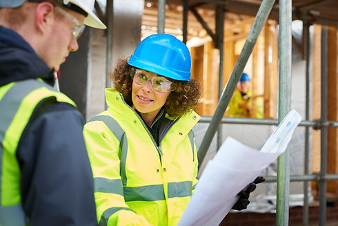 a female construction worker stands on a building site housing development and instructs a