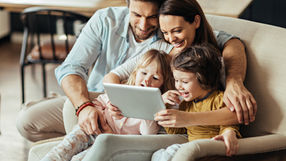 A smiling family looking at a tablet