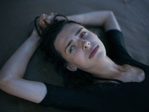 An exasperated woman laying down on sand.